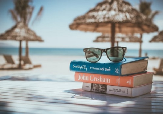 Taula a la platja amb llibres i ulleres de sol